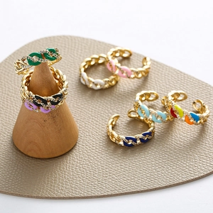 Colorful enamel chain rings with zircon inlays on wooden stand and leather surface