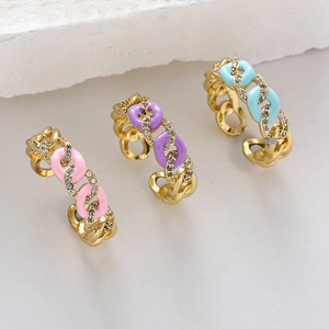 Macro detail of three colorful enamel chain rings with micro-set zircons in gold plating