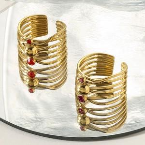 Macro detail of gold-plated multi-layer open ring with red zircon on wave mirror base