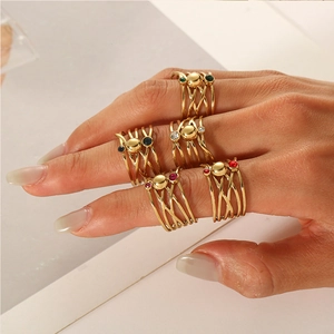 Close-up of stacked gold rings with colorful gemstones and crossed band design