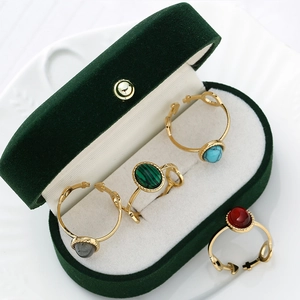 Macro shot of gold stainless steel rings with colorful oval natural stones in a velvet box