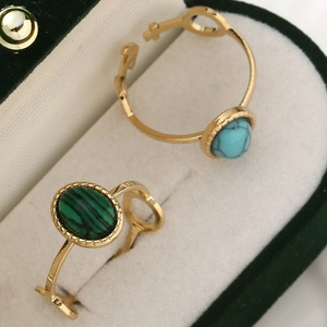 Macro detail of gold rings with turquoise and malachite stones on green velvet