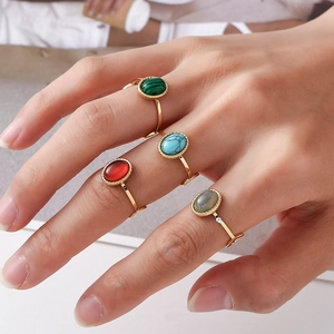 Detail shot of four vintage gold rings with colorful oval stones worn by a model