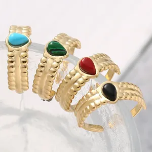 Macro shot of gold teardrop open rings featuring textured bands and colorful stones