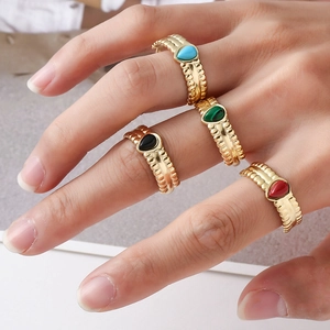 Detail of four teardrop-shaped gemstone rings with gold-plated ribbed bands