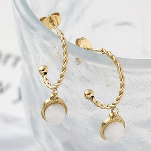 Détails macro des boucles d'oreilles torsadées avec pierre naturelle blanche en or 18k