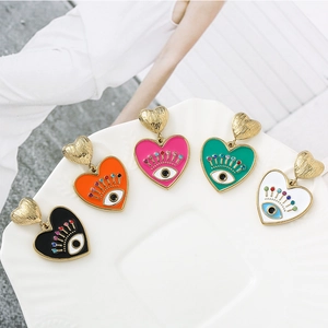 Détails de boucles d'oreilles cœur en émail coloré avec un motif œil en strass brillant