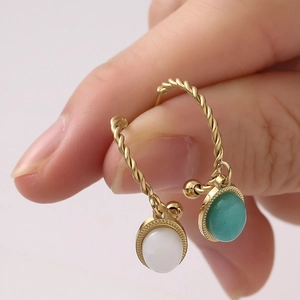 Vue macro de boucles d'oreilles torsadées dorées avec gouttes de pierre blanche et bleue