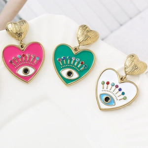 Détails macro des boucles d'oreilles cœur en émail avec motif œil et cristaux colorés