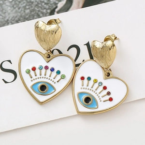 Détail macro de boucles d'oreilles en cœur avec œil porte-bonheur en strass et métal doré