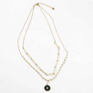 Detalle del collar de doble capa dorado con colgante de estrella negra y eslabones de clip