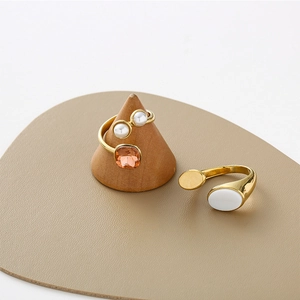 Detailed view of an oval white shell inlay and faceted gemstone on a gold-plated ring