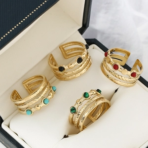 Detail of four gold multi-layer adjustable rings with colorful gemstone inlays on velvet