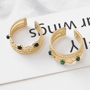 Detail of two layered gold rings with black and green malachite stones on a white card
