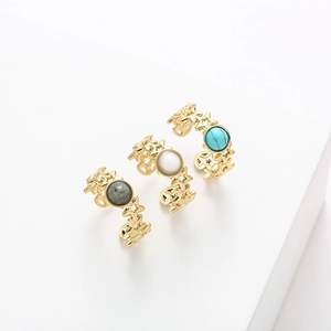Close-up of three gold star open rings with set natural stones on white display