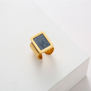 Close-up of golden square ring with gray marble inlay on minimalist display stand
