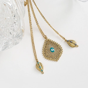 Détail du collier filigrane doré avec pendentif œil porte-bonheur sur fond blanc épuré