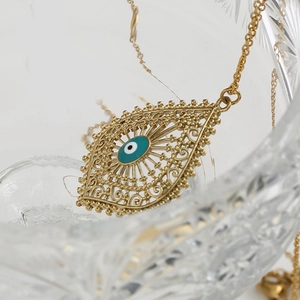 Collier goutte œil maléfique doré avec pendentif en émail bleu sur surface en cristal