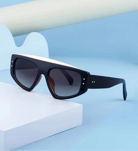 Détails de lunettes de soleil larges avec points métalliques et verres dégradés sur fond bleu