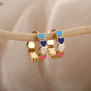 Chic gold hoop earrings with multi-colored enamel hearts on a rustic wooden display