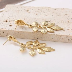Elegant gold leaf earrings with French pleated texture on premium stone backdrop