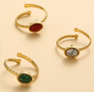 Detailed view of three gold rings featuring oval turquoise, malachite, and agate gemstones