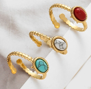 Detailed view of three gold-plated adjustable rings with red, white, and turquoise stones