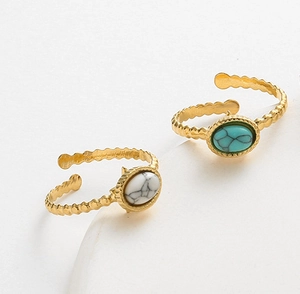 Macro shot of oval white marble and turquoise stones set in gold wavy adjustable rings