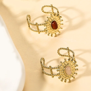 Dettaglio ravvicinato di anelli a girasole dorati con pietre rosse e rosa in stile boho