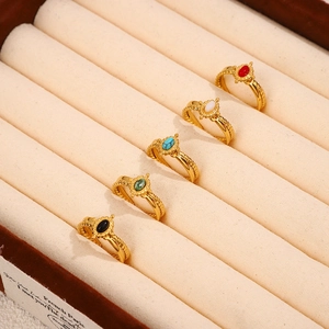Macro detail of five vintage oval stone rings with twisted gold bands in a beige box