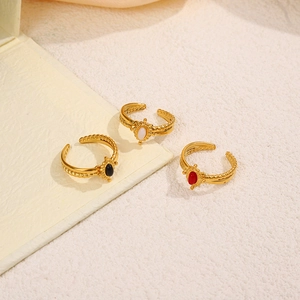 Vintage gold adjustable rings set with black, white, and red stones on textured surface