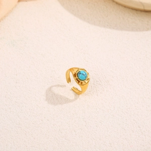 Détail d'une bague vintage en plaqué or avec une pierre turquoise ronde et un bord perlé poli