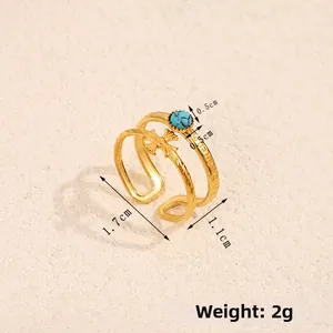 Detail of double-layer 18K gold stainless steel ring with turquoise and cross symbol