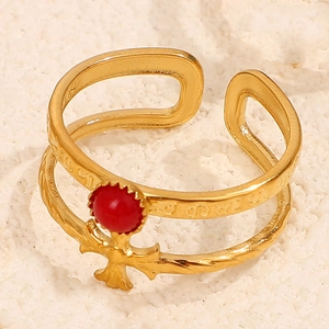 Macro detail of 18K gold stainless steel cross ring with a red gemstone on white stone