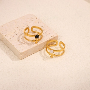 Detail of adjustable double-layer 18K gold rings with cross charms and black and white stones