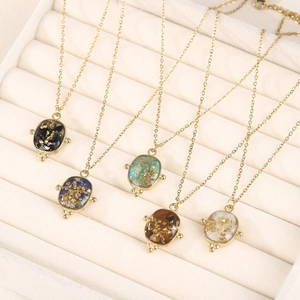 Lot de cinq colliers en acier inoxydable doré avec pendentifs ovales en résine colorée