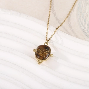 Détail macro du pendentif ovale ambré avec paillettes d'or sur une chaîne dorée