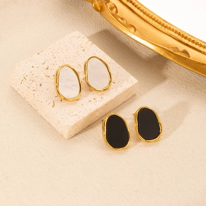 Detail of vintage oval gold-rimmed earrings in black and white on stone background