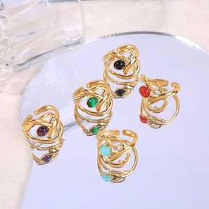 Multi-layer crisscross gold rings with colorful round stones on a reflective mirror
