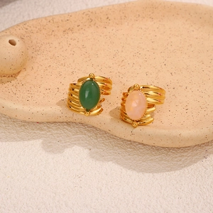 Detail of vintage gold rings with green and pink gemstones on a ceramic tray