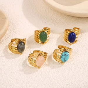 Detail of five stackable gold steel rings featuring colorful oval natural gemstones