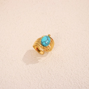 Macro view of a gold titanium ring featuring a layered band and natural turquoise stone