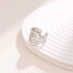 Minimalist silver wavy spiral stainless steel open ring on aesthetic white stand