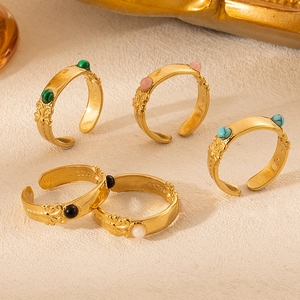 Detailed macro of vintage gold rings featuring embossed flowers and colorful stone beads