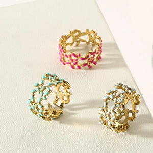 Close-up of golden floral leaf rings with colorful enamel detailing and cutout design