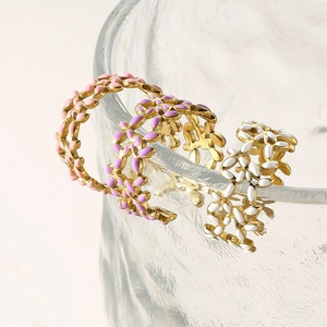 Detail of three colorful enamel flower rings in pink, purple and white on glass edge