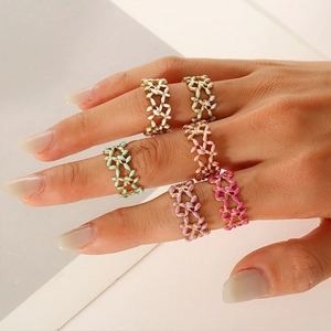 Detail of six colorful enamel floral rings in pastel shades on a female hand
