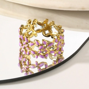 Macro shot of gold floral ring featuring purple enamel petals and artistic hollow design