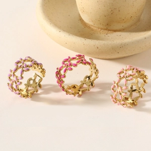 Close-up of gold stainless steel rings with colorful floral enamel leaf designs