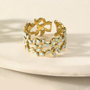 Macro detail of leaf-shaped open ring with light blue enamel on gold-plated band